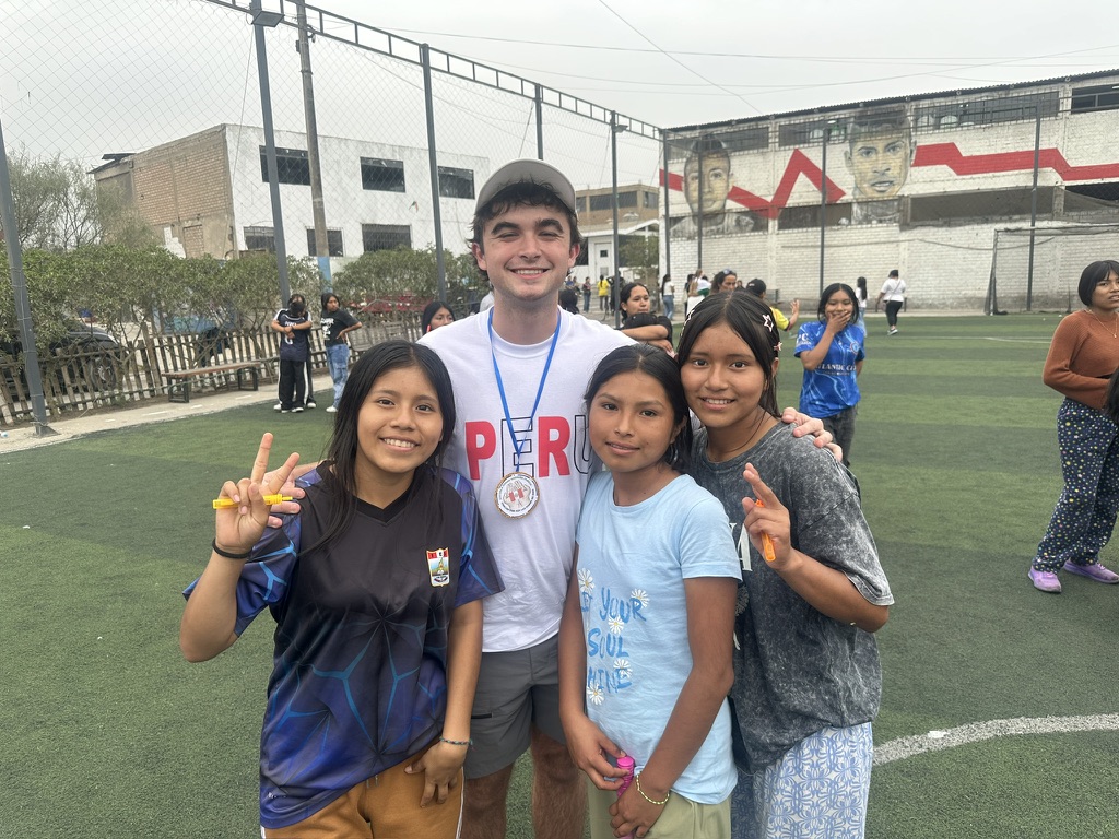 Donovan Burke with students on a soccer field in Peru